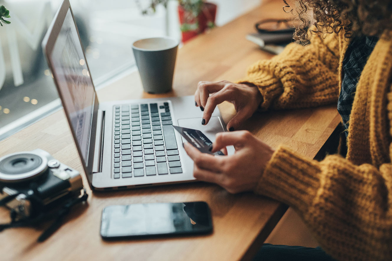 Woman holding card at laptop.